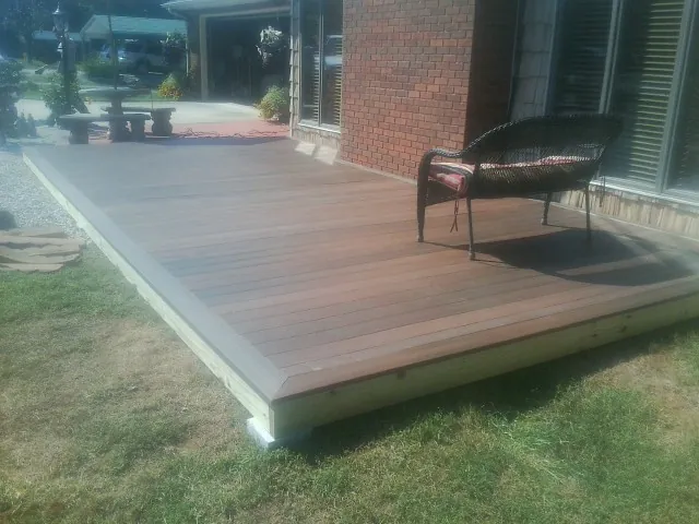 New wood deck and wicker chair beside a brick house in Charlestown