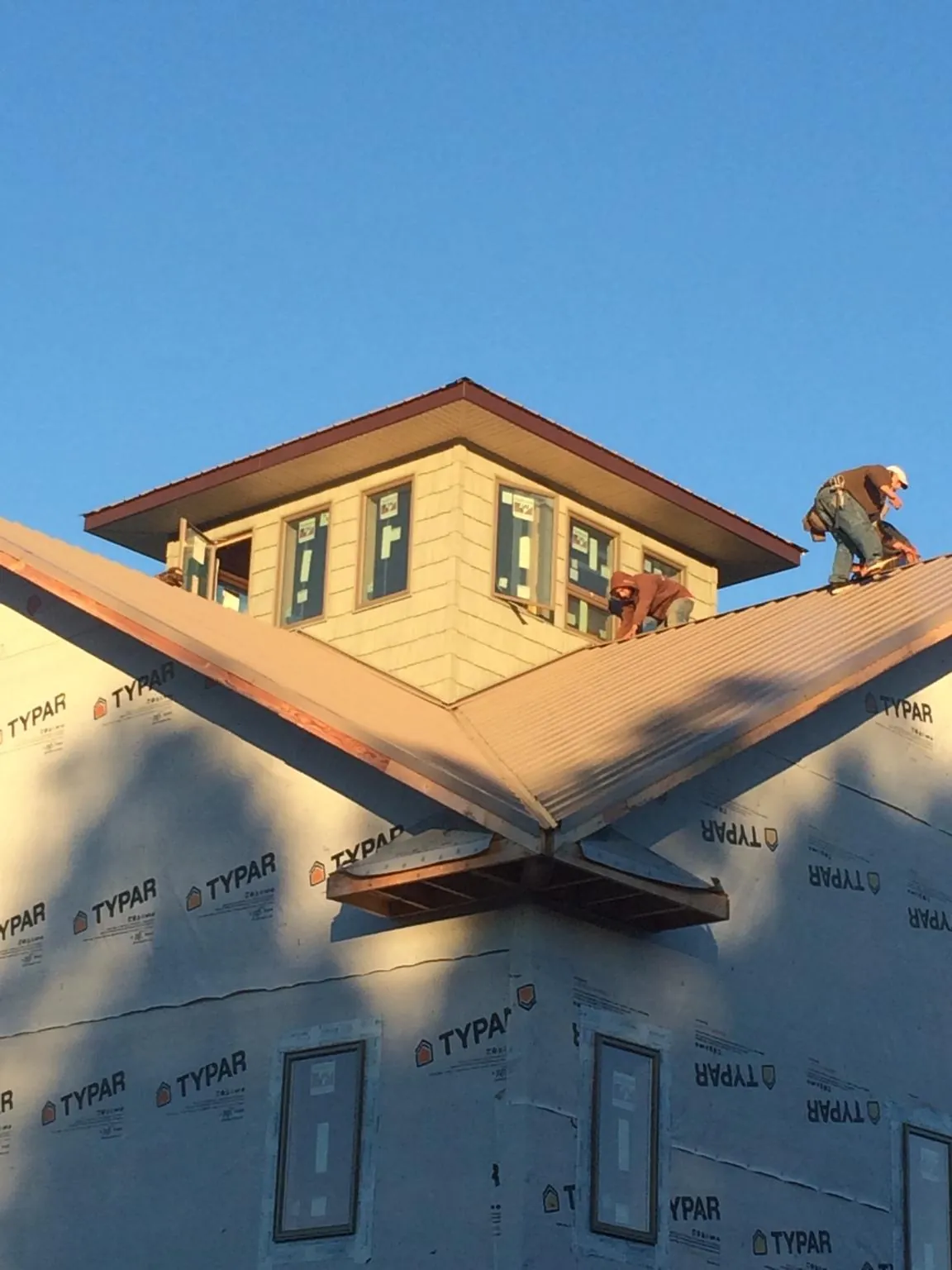 Roofers working around a rooftop cupola on a new metal roof at sunset — Roof Waterproofing in Charlestown by Roofing Brothers